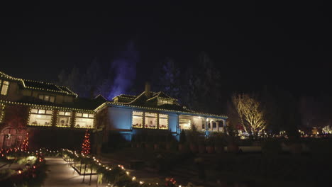 Weitwinkelaufnahme-Eines-Mit-Weihnachtsbeleuchtung-Geschmückten-Hauses-Und-Rauch-Aus-Dem-Schornstein,-Nacht