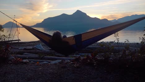 Woman-watching-ocean-sunset-from-hammock-in-oceanfront-campsite