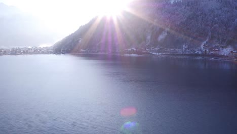 Vuelo-Sobre-Un-Lago-En-Las-Colinas-Austriacas-En-Invierno-Y-Una-Llamarada-Solar