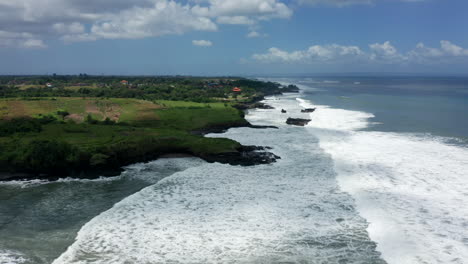 Aerial-drone-footage,-coastline-with-black-rocks-in-Bali