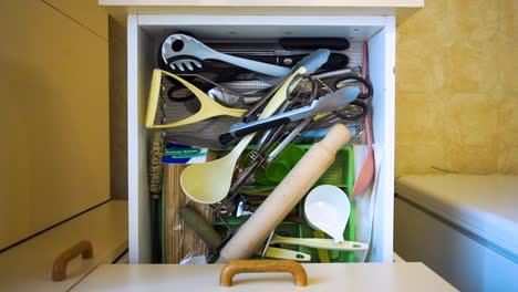 Kitchen-draw-full-of-messy-utensils-is-opened,-left-open,-and-then-closed
