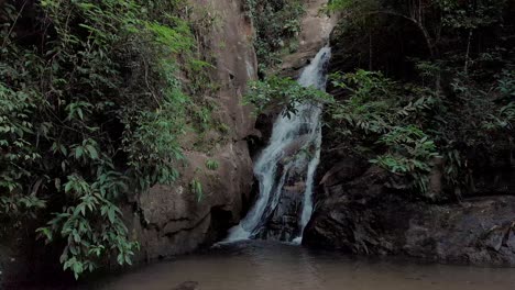 Relatively-still-floating-shot-of-a-small-waterfall-mouthing-into-a-pond-in-the-tropical-mountain-forest-of-Rio-de-Janeiro