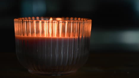 Burning-candle-in-the-glass-cup,-moving-fire-by-wind-blowing-in-the-darkness