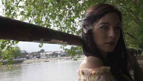 Portrait-of-an-attractive-latina-model-posing-next-to-river-Thames-in-London,-looking-at-the-camera-with-a-floral-dress