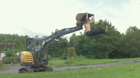 Topless-fit-young-male-does-behind-neck-pull-ups-and-l-sit-exercise-on-digger-bucket
