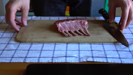 Chef-holding-a-cutting-board-with-a-rack-of-lamb-and-a-chef-knife-on-top