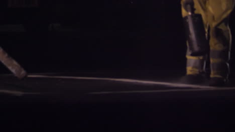 Unrecognizable-road-workers-line-painting-on-a-main-road-in-the-UK-at-night-in-slow-motion