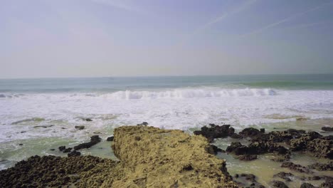 Nature-Sea-Ocean-Shore-Stones-Rocks-Waves-Cliff-Sand-Seaweed-Sunny-Daylight-Traveling-Tilt-Shot-4K