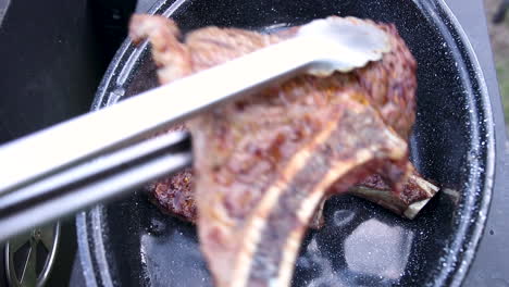 View-from-top-serving-juicy-and-tasty-looking-steak-into-enamel-casserole-with-a-slow-zoom-in-effect