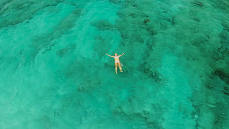 Girl-swimming-and-floating-in-an-amazing-clear-green-tinted-ocean-water-during-a-holiday