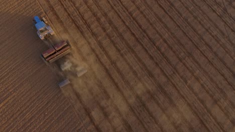 Sowing-fields-with-tractor-and-seeder-in-dusty-field-aerial-view