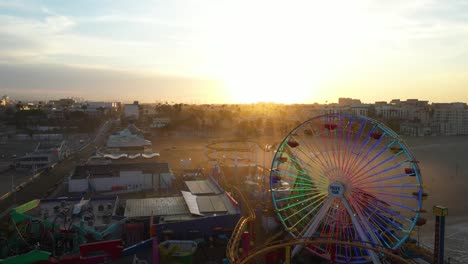 Gorgeous-aerial-fly-over-ferris-wheel-during-sunset-golden-hour-on-the-beach
