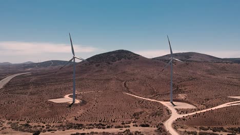 Two-Wind-turbines-on-the-front,-aerial-shot,-La-Serena,-Chile