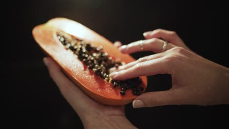 Female-hands-hold-fresh-juicy-papaya-cut-in-half