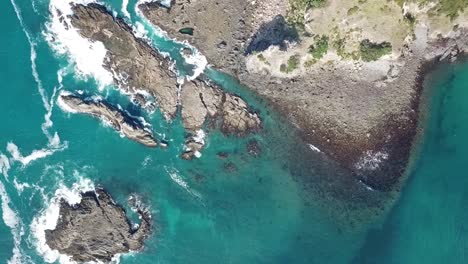Aerial-shot,-drone-view-looking-above-panning,-waves-hitting-the-rocks-Medlands-beach,-Great-Barrier-Island,-New-Zealand