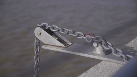 Chain-on-a-pulley-system-hanging-over-the-sea-in-slow-motion