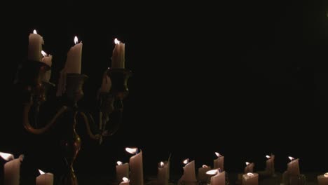 A-group-of-white-candles-some-on-a-candelabra-lit-up-and-running-for-a-while-in-slow-motion