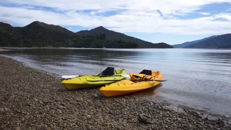Two-sea-kayaks-on-rocky-beach-in-Marlborough-Sounds,-New-Zealand