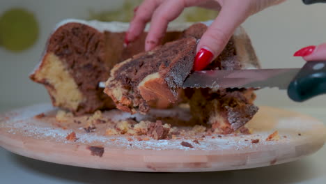 Traditional-marble-cake-on-wooden-plate,-femal-hands-cutting-cake-into-slices