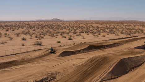 Aerial-profile-view-flying-by-motocross-motorcycle-rider-on-desert-racetrack