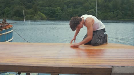 Man-sands-down-wood-roof-planking-of-boat-by-hand.