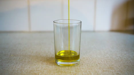 Cooking-oil-being-drizzledinto-glass-on-kitchen-bench