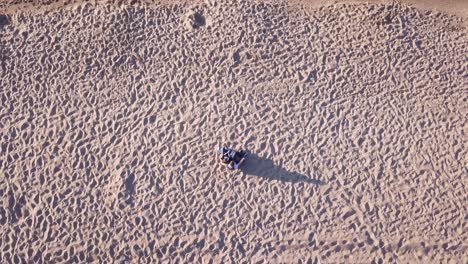 Luftaufnahme-Eines-Jungen-Paares,-Das-Am-Sandstrand-Sitzt-Und-Sich-Umarmt