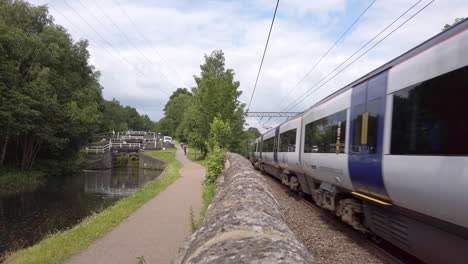 Static-Shot-of-a-Northern-Train-Passing-By-Canal-Locks-as-it-Travels-Away-from-Leeds-on-a-Summer’s-Day