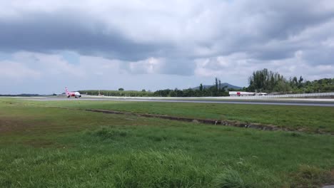 Landschaftsansicht-Der-Landebahn-Des-Flughafens,-Während-Das-Airasia-Flugzeug-Airbus-A320-Bei-Bewölktem-Tag-Auf-Der-Landebahn-Wartet---1080-HD-Video