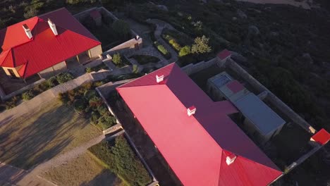 Aerial-shot-of-red-roof-properties-on-the-hill-with-two-beaches-and-ocean-view-next-to-a-lighthouse