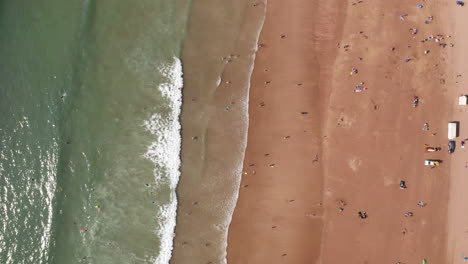Aerial-Flyover-of-a-Golden-Sandy-Beach-in-North-Devon-with-People-Sunbathing-and-a-Truck-Driving-Down-the-Beach