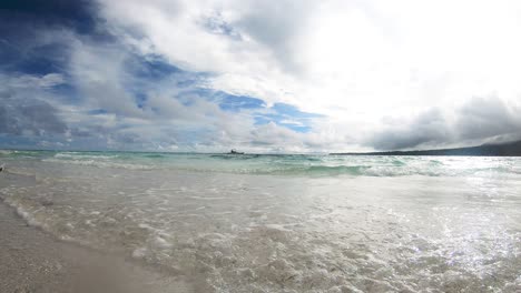 Olas-Llegando-A-Tierra-En-Una-Playa-Tropical-Con-Cielo-Azul-Nubes-Blancas-Y-Barco-Pasando-En-El-Fondo-Y-La-Isla-Filipinas-4k
