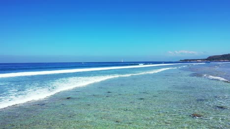 Weiße-Wellen-Plätschern-Und-Schäumen-über-Dem-Flachen,-Ruhigen-Wasser-Der-Türkisfarbenen-Lagune-Voller-Felsen-Und-Kieselsteine-Unter-Klarem,-Offenem,-Blauem-Himmel-In-Malaysia