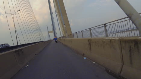 2-of-3-parts-of-crossing-the-Phu-My-Bridge-on-Motorcyle-showing-the-approach,-structure-of-the-bridge,-other-vehicles-and-shipping-on-the-river-below