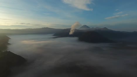 Drone-shot-moving-towards-the-Bromo-volcano,-rumbling-and-smoking
