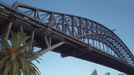 Wunderschönes-Schwenken-Und-Nahaufnahme-Der-Sydney-Harbour-Bridge-Unterhalb-Der-Brücke-Bei-Sonnenuntergang