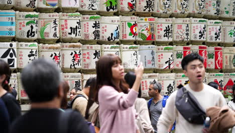 Slow-motion-of-tourists-visiting-decorative-sake-barrels-in-Meiji-Jingu-Shrine,-Tokyo