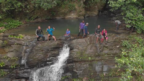 Epic-revealing-aerial-of-hikers-relaxing-on-the-top-of-a-cascading-waterfall