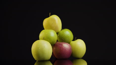 Ein-Haufen-Grüner-Äpfel-Auf-Einer-Spiegelplatte-Auf-Schwarzem-Hintergrund