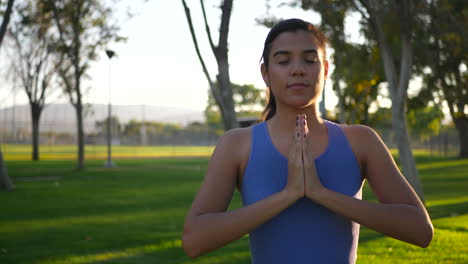 Eine-Schöne-Junge-Hispanische-Yogi-Frau,-Die-Bei-Sonnenaufgang-In-Einer-Einbeinigen-Gebetshände-Im-Park-Meditiert