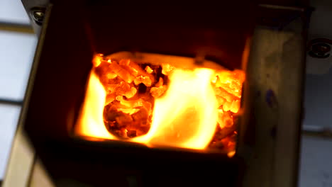 Slow-motion-hand-held-shot-of-a-yellow-flame-firing-out-he-back-of-a-table-top-pizza-oven,-flame-coming-out-of-a-grill