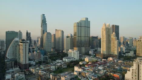 Bangkok-skyline-during-golden-hour-with-clear-blue-skies,-aerial-view