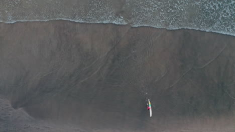 Aerial-Drone-Shot-of-Lone-Surfer-Walking-Out-of-Ocean-On-Deserted-Beach-in-Tambor,-Costa-Rica-4K-Top-Down-Camera-Going-Down-Fast