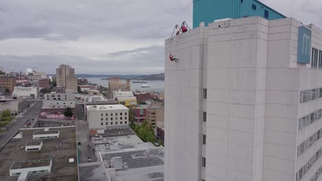 aerial-shot---a-person-rappels-off-the-edge-of-a-skyscraper-in-Tacoma-WA