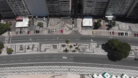 Top-down-pan-showing-Copacabana-beach-and-boulevard-road-and-pavement-on-a-bright-sunny-summer-day-with-little-traffic-during-the-COVID-19-Corona-virus-outbreak
