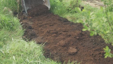 Emptying-wheelbarrow-of-compost-over-soil-for-planting