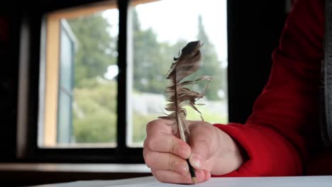 Woman's-Hand-Writing-With-A-Quill-Pen-Inside-A-Cabin-In-The-Woodland---close-up