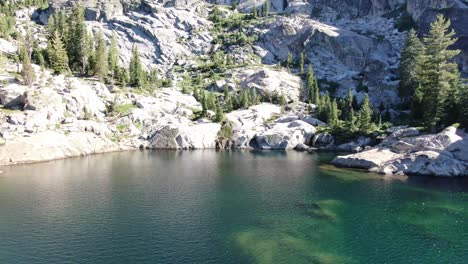4K-drone-footage-cinematic-shot-pulling-away-from-waterfall-at-a-high-altitude-alpine-lake-in-Desolation-Wilderness-during-a-backpacking-camping-trip-with-friends-and-family-camping-in-the-forest