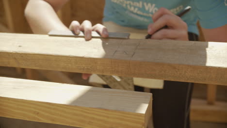 Female-Construction-Worker-Marks-Wood-With-Speed-Square,-Close-Up