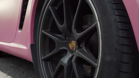 Close-up-on-Porsche-branded-wheel,-of-pink-coated-Porsche-Boxster-cabriolet